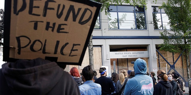 A protester holds a sign that reads "defund the police" after Seattle Police vacated the department's East Precinct and people continue to rally against racial inequality and the death in Minneapolis police custody of George Floyd, in Seattle, Washington, U.S. June 8, 2020. (REUTERS/Jason Redmond)
