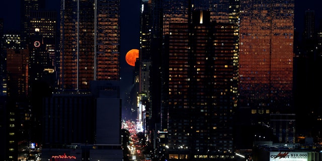 A full moon known as a strawberry moon rises over 42nd Street in New York United States