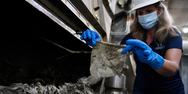 In this May 28, 2020, file photo Lyn Riggins, WSSC Water spokesperson, holds up a wipe that was collected along with other debris at a pumping station in Washington. Sewer systems are battling the "wipe monster" from all the wipes and other debris since pandemic that are clogging up pumping stations. (AP Photo/Susan Walsh)