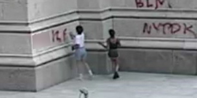 NYPD says surveillance cameras captured pair vandalizing St. Patrick's Cathedral in Midtown Manhattan Saturday with spray paint cans. (NYPD)