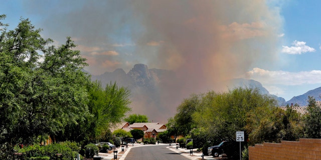 The Bighorn Fire backdrops a community along the western side of the Santa Catalina Mountains, Friday, June 12, 2020, in Tucson Ariz.