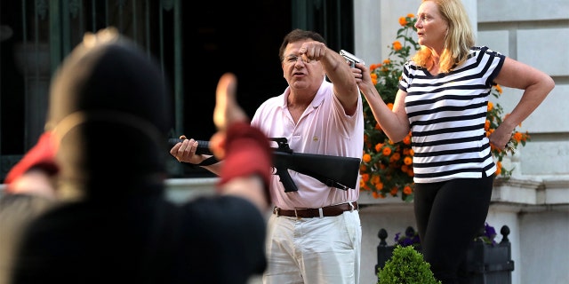 Armed homeowners standing in front of their house along Portland Place confront protesters as they march to Mayor Lyda Krewson's house on Sunday, June 28, in the Central West End in St. Louis. (Laurie Skrivan/St. Louis Post-Dispatch/Tribune News Service via Getty Images)