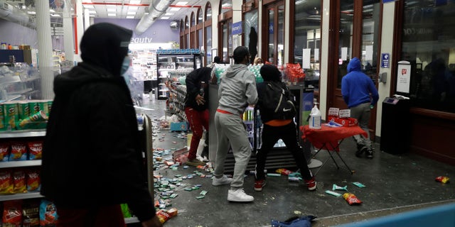 People grab items inside a pharmacy that had its windows broken in New York, Monday, June 1, 2020. (AP Photo/Seth Wenig)