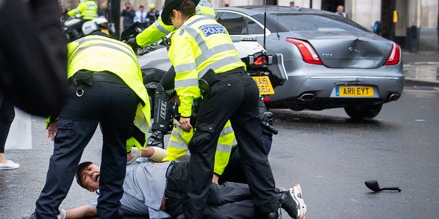 Police detained a man after he appeared to run in front of Johnson's car. (Victoria Jones/PA via AP)