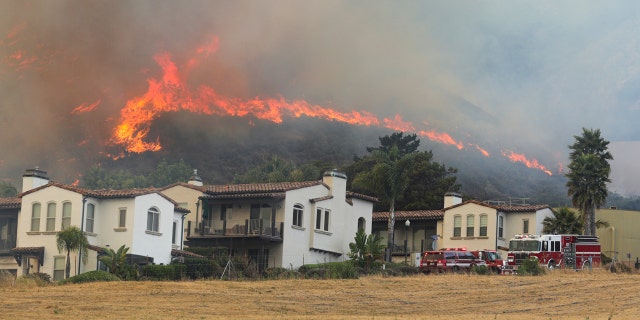 A brush fire burns above houses near U.S. 101 in Pismo Beach, Calif., June 15.