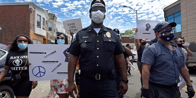 Lt. Zack James of the Camden County Metro Police Department marches along with demonstrators in Camden on Saturday to protest the death of George Floyd. (April Saul via AP)
