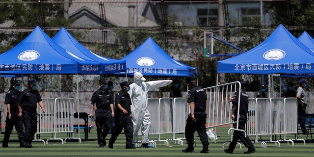 A worker directs security guards as they set up barricades for people who were living surrounding the Xinfadi wholesale market and those have visited to the market to conduct a nucleic acid test at a stadium in Beijing, Sunday, June 14, 2020.