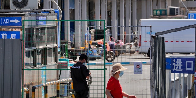 A security guard locks with chain the fence of the seafood wholesale market main entrance which was closed for inspection in Beijing, Sunday, June 14, 2020.