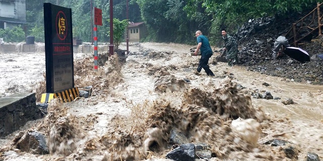 In this photo released by Xinhua News Agency, government workers try to stem a breach in a dike from floodwater in Wuxi County, southwest China's Chongqing municipality, June 12, 2020.