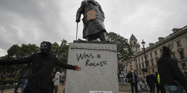 Protesters gather around a vandalized Winston Churchill statue in Parliament Square on Sunday. (AP)