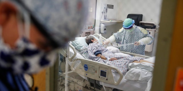 FILE - In this April 20, 2020, file photo, resident physician Leslie Bottrell stands outside a room at an Intensive Care Unit as a nurse suctions the lungs of a COVID-19 patient at St. Joseph's Hospital in Yonkers, N.Y. A U.S. government report says death rates are 12 times higher for coronavirus patients with chronic illnesses than for others who become infected. The Centers for Disease Control and Prevention report Monday, June 15 highlights the dangers posed by these conditions. They include heart disease, diabetes and chronic lung ailments, such as asthma or emphysema. (AP Photo/John Minchillo, File)