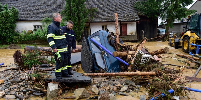 Firefighters look on a car trapped in a flooded area in Brevenec, the part of the village of Sumvald in the Olomouc region, Czech Republic, Monday, June 8, 2020.