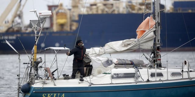 Juan Manuel Ballestero stands on his boat in Mar del Plata, Argentina, Thursday, June 18, 2020. Ballestero crossed the Atlantic on a small sailboat, setting off from the port of Porto Santo in Portugal on March 24 and finally reaching Mar del Plata on Wednesday to be reunited with his parents after flights to Argentina were cut due to the COVID-19 lockdown. (AP Photo/Vicente Robles)