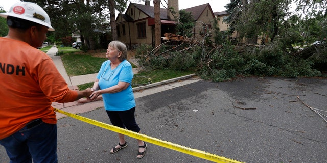 Homeowner Donna Purdy, right, thanks a tree trimmer after he checked the fallen tree that barely missed the woman's home east of Washington Park after a derecho ripped through the region on Saturday, June 6, 2020.