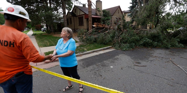 Homeowner Donna Purdy, right, thanks a tree trimmer after he checked the fallen tree that barely missed the woman's home east of Washington Park after a derecho ripped through the region on Saturday, June 6, 2020.