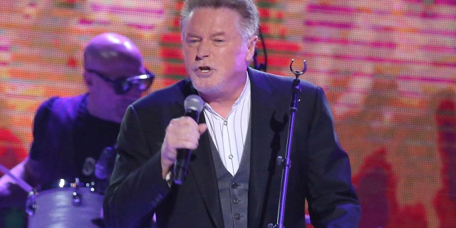 Don Henley performing in a suit with a microphone in 2017