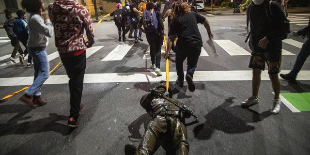 Protesters drag a figure pulled from the Confederate monument at the State Capitol down Salisbury Street in Raleigh, N.C., on Juneteenth, Friday, June 19, 2020.