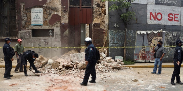 A policeman removes rubble from a building damaged by an earthquake in Oaxaca, Mexico, Tuesday, June 23, 2020.