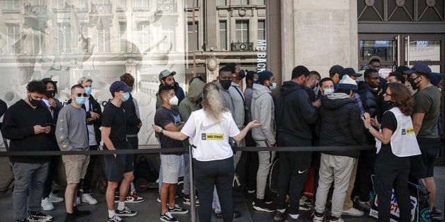 Nike employees speak to people lining up outside the Niketown shop in hopes of getting them to maintain social distancing in London on Monday. (AP)