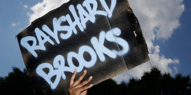 A protester holds up a sign on Saturday, June 13, 2020, near the Wendy's restaurant where Rayshard Brooks was shot and killed by police Friday evening following a struggle in the restaurant's drive-thru line in Atlanta. (Associated Press)