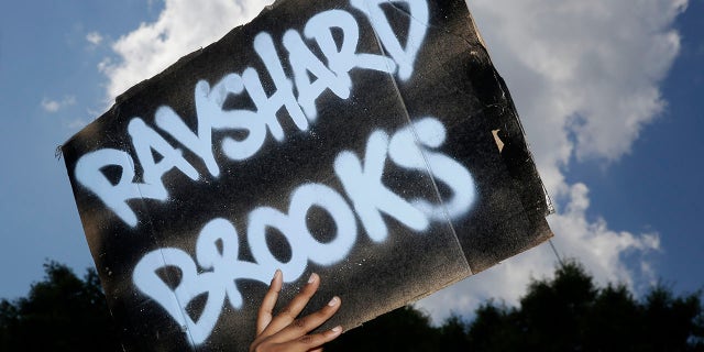 A protester holds up a sign on Saturday, June 13, 2020, near the Wendy's restaurant where Rayshard Brooks was shot and killed by police Friday evening following a struggle in the restaurant's drive-thru line in Atlanta. (Associated Press)