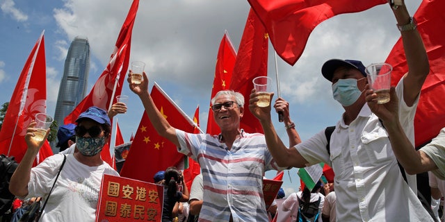 Pro-China supporters holding Chinese national flags, toast during a rally to celebrate the approval of a national security law for Hong Kong, in Hong Kong, on Tuesday. (AP)