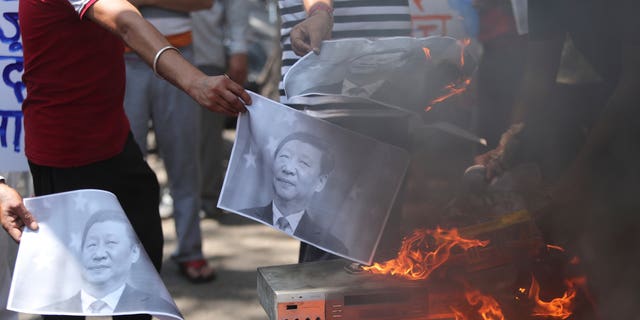 Indians burn photographs of Chinese President Xi Jinping during a protest against the Chinese government in Jammu, India, June 2020. (AP)