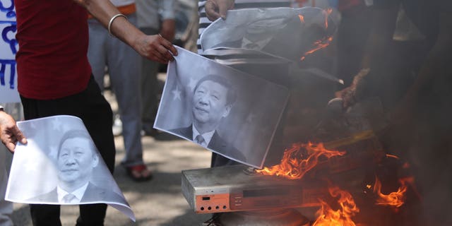 Indians burn photographs of Chinese President Xi Jinping during a protest against the Chinese government in Jammu, India, June 2020. (AP)