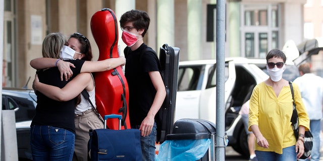 Giuseppina Niglio, from Salerno, southern Italy, hugs her children Roberta and Alessandro, students at the Lugano School of music Conservatory in Switzerland, at the Italian-Swiss border, in Ponte Chiasso, Italy, Wednesday, June 3, 2020. Italy opened regional and international borders in the final phase of easing its long coronavirus lockdown, (AP Photo/Antonio Calanni)