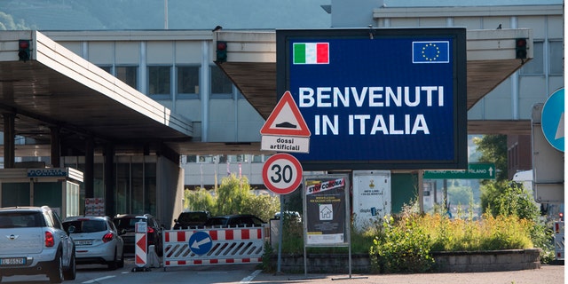 Cars cross the border station Chiasso Brogeda between Switzerland and Italy, in Chiasso, Switzerland, Wednesday, June 3, 2020. Italy opened its borders to the citizens of the EU and Switzerland this June 3, after the coronavirus lockdown with closed borders and travel restrictions. The slogan on the video screen reads: 'Welcome to Italy'. (Alessandro Crinari/Keystone via AP)