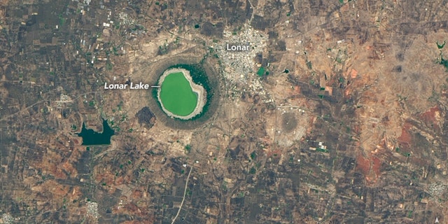 In this NASA photo from May 25, 2020, Lonar Lake can be seen with a green color at the surface.