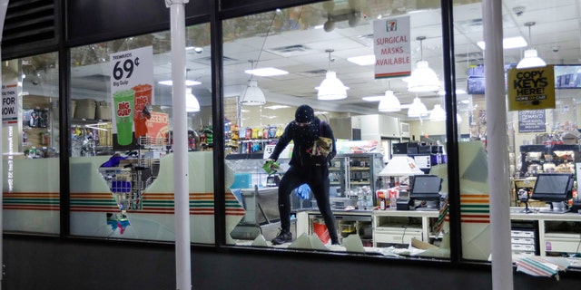 A person carries merchandise from a 7-Eleven store, Monday, June 1, 2020, in New York. (AP Photo/Frank Franklin II)