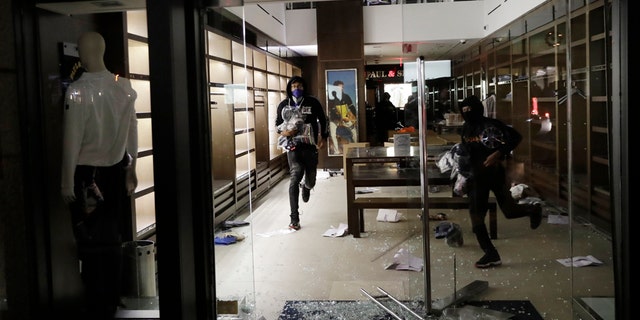 People carry merchandise out of a store that was broken into in New York, Monday, June 1, 2020. (AP Photo/Seth Wenig)