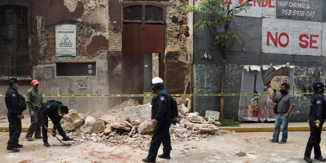 A policeman removes rubble from a building damaged by an earthquake in Oaxaca, Mexico, June 23.