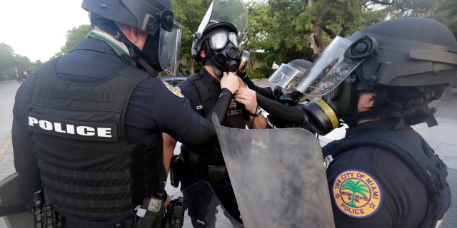 City of Miami police officers gear up as they prepare for any problems with protesters Sunday, May 31, 2020, in Miami. (AP Photo/Wilfredo Lee)