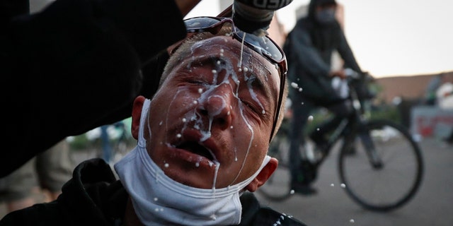 A protester is assisted with a solution to help neutralize the effects of tear gas fired by police outside the Minneapolis 5th Police Precinct, Saturday, May 30, 2020, in Minneapolis. Protests continued following the death of George Floyd, who died after being restrained by Minneapolis police officers on Memorial Day. (AP Photo/John Minchillo)
