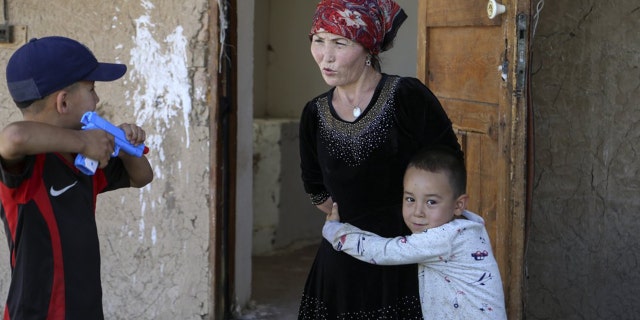 Alif Baqytali abraza a su madre, Gulnar Omirzakh, en su nuevo hogar en Shonzhy, Kazajstán.  Omirzakh, una kazaja étnica nacida en China, dice que se vio obligada a obtener un dispositivo anticonceptivo intrauterino y que las autoridades en China amenazaron con detenerla si no pagaba una gran multa por dar a luz a Alif, su tercer hijo.