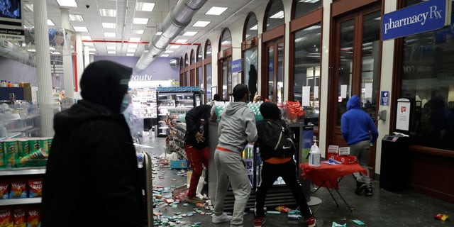 People grab items inside a pharmacy that had its windows broken in New York City early Monday. (AP)