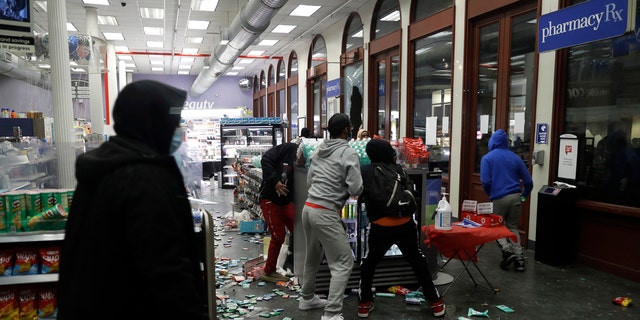 People grab items inside a pharmacy that had its windows broken in New York, Monday, June 1, 2020.