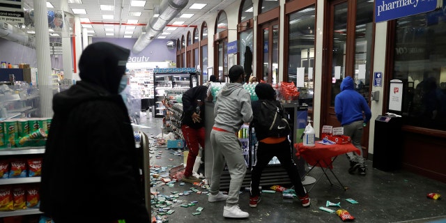 People grab items inside a pharmacy that had its windows broken in New York, Monday, June 1, 2020.