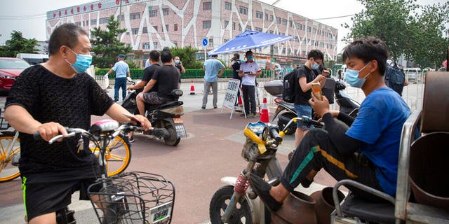 People wearing face masks to protect against the new coronavirus stop at a checkpoint outside the Xinfadi wholesale food market district in Beijing, Saturday, June 13, 2020. Beijing closed the city's largest wholesale food market Saturday after the discovery of seven cases of the new coronavirus in the previous two days.