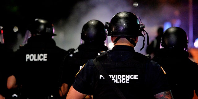 Police officers and National Guard soldiers make their way through a smoke filled street as they chase and confront protesters after curfew and after a peaceful Black Lives Matter rally in Providence, Rhode Island on June 5, 2020. (Photo by Joseph Prezioso / AFP) (Photo by JOSEPH PREZIOSO/AFP via Getty Images)