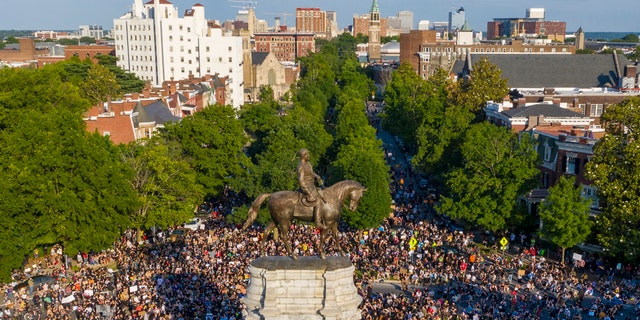 This Tuesday, June 2, 2020 file photo shows a large group of protesters gather around the statue of Confederate General Robert E. Lee on Monument Avenue near downtown in Richmond, Va. (AP Photo/Steve Helber, File)