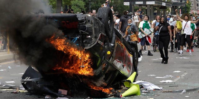 In this May 30, photo, protesters demonstrate as a Salt Lake City police vehicle burns, in Salt Lake City. Police have so far charged eight people in the incident. (AP Photo/Rick Bowmer)