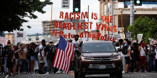 A protester sits out of the window of a car with an American flag as a youth-led protest group walks towards the Seattle Police Department's West Precinct in Seattle, Washington, U.S. June 10, 2020. 