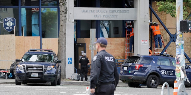 Workers put up plywood over the windows of a Seattle police precinct Monday, June 8, 2020, in Seattle. (AP Photo/Elaine Thompson)