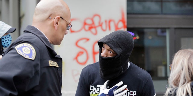 Demonstrator Keith Brown, right, talks with Seattle Fire Dept. Assistant Chief Willie Barrington as they plan to remove makeshift barricades protesters had put up in the streets next to a Seattle police precinct Tuesday, June 9, 2020, in Seattle. (AP Photo/Elaine Thompson)