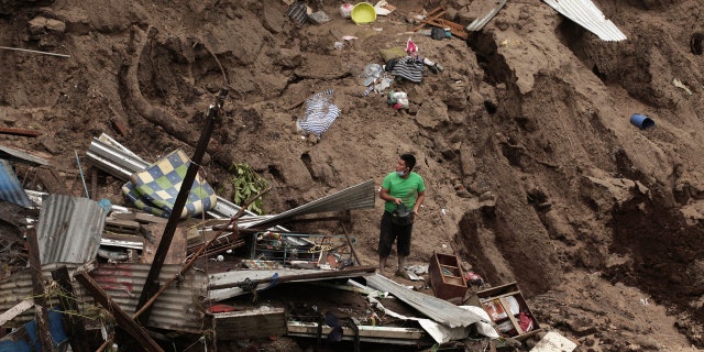 A man seeks to salvage some of his belongings from what used to be his home, destroyed by the waters of the Acelhuate River, in the New Israel Community of San Salvador, El Salvador, Sunday, May 31, 2020.