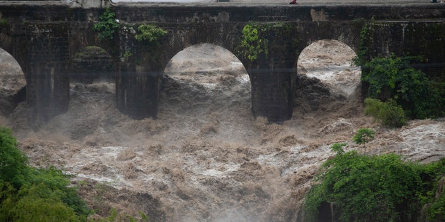 The swollen Los Esclavos River flows violently under a bridge during tropical storm Amanda in Cuilapa, eastern Guatemala, Sunday, May 31, 2020.