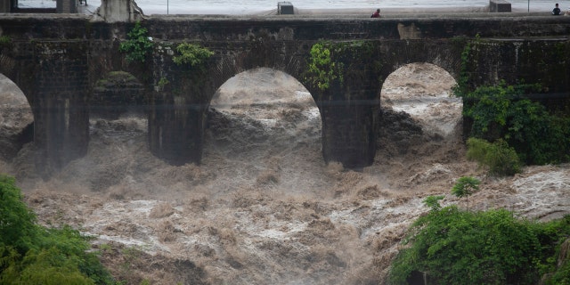 The swollen Los Esclavos River flows violently under a bridge during tropical storm Amanda in Cuilapa, eastern Guatemala, Sunday, May 31, 2020.